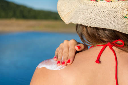 Young woman applying sun lotion on summer vacationの写真素材