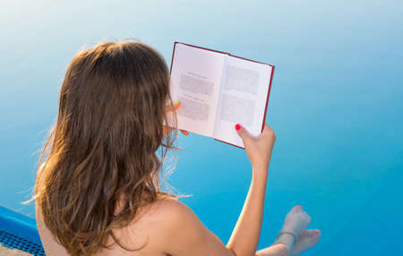 Girl reading by the swimming pool. Summer literatureの写真素材