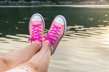 Enjoying by the lake. Woman legs wearing pink sneakersの写真素材