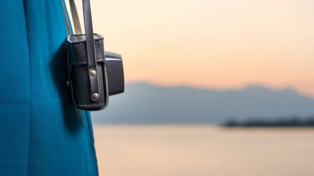 Vintage camera hanging from womans shoulder by the lake