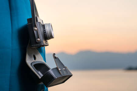 Vintage camera hanging from womans shoulder by the lakeの写真素材