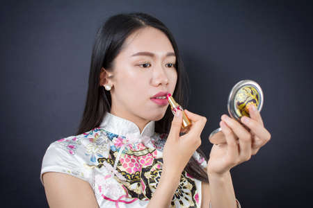 Beautiful young asian woman applying makeup on her faceの写真素材