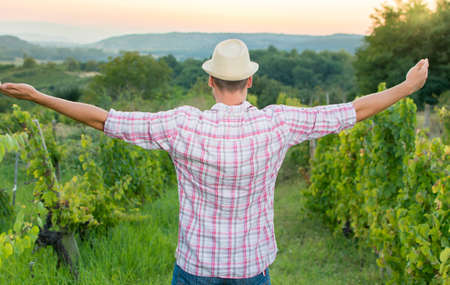 Happy farmer enjoying among the grape rows