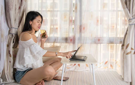 Young woman using lap top by the window at homeの写真素材