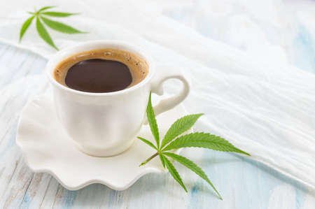 Hot coffee and marijuana leaves on a tableの写真素材