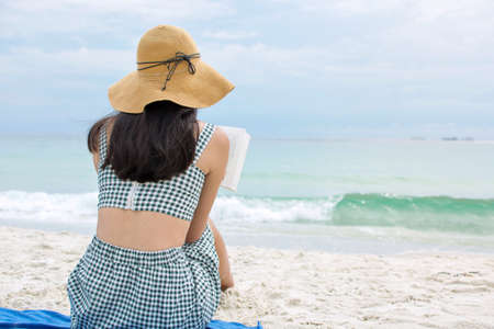 Young woman reading a book on the beachの写真素材