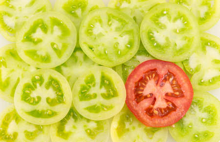 green tomatoes sliced into circles and arranged together next to a red tomato slice
