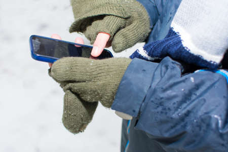 Male hands in gloves using a smartphone in winter timeの写真素材