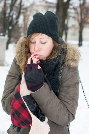 woman warming up hands in snow covered park