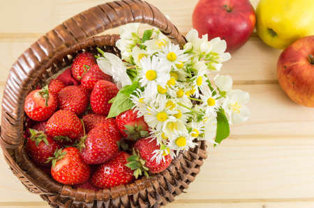 strawberries and chamomile in a woven wooden basketの写真素材