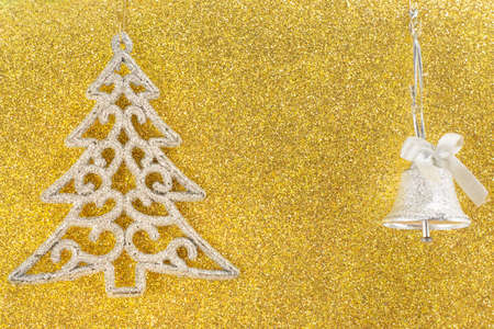 Silver christmas tree ornament on golden background with a christmas bellの写真素材