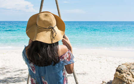 Girl sitting on a wooden swing on the beach. Summer holiday goalsの写真素材