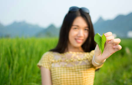 Happy girl holding leaf in a rice fieldの写真素材