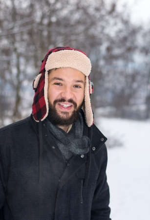 Happy man standing outdoors while it is snowing