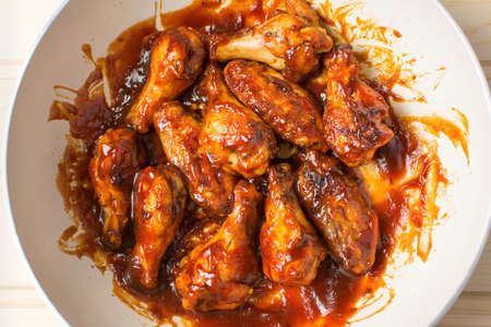 Chicken wings baking on a ceramic pan in sauceの写真素材