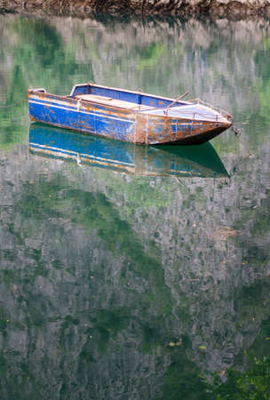 Boat floating on calm green colored lake waterの写真素材
