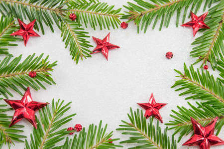 Fir tree branches and star shaped Christmas ornaments on sparkling backgroundの写真素材