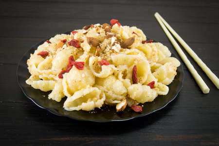 Sweet pasta with nuts, almonds and goji berries on a plate