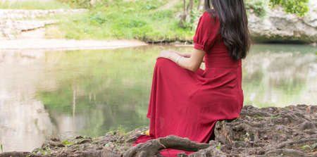 Fashionable woman sitting next to a river aloneの写真素材