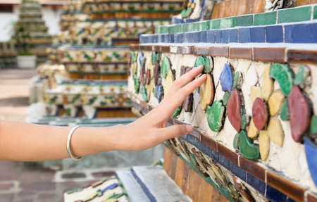 Female hand touching Buddhist monument rocks in a temple yardの写真素材