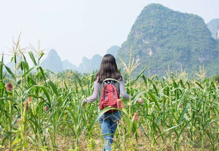 Girl walking in a corn field with karst sceneryの写真素材