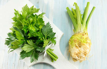 whole celery on a white cutting board on a blue tableの写真素材