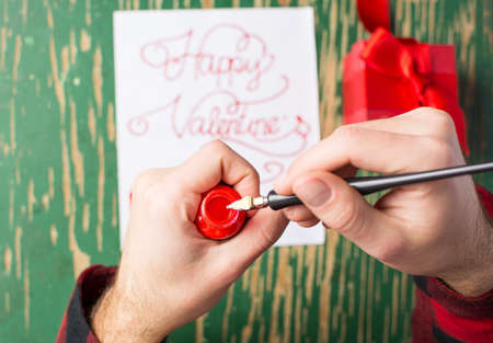 Male hands writing a calligraphy Valentines day card