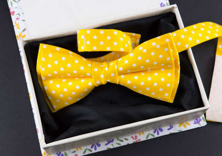 Yellow bow tie in a present box on black tableの写真素材