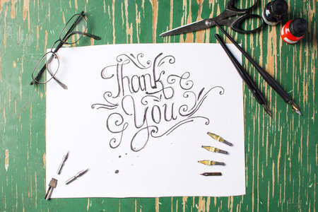 Thank you note calligraphy with writing equipment on the tableの写真素材