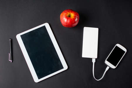 Red apple and white electronic devices. Snack at workの写真素材