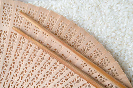 Hand fan and chopsticks on top of white rice backgroundの写真素材