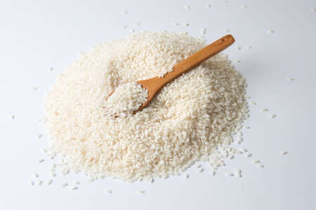 Wooden spoon in pile of rice on white backgroundの写真素材