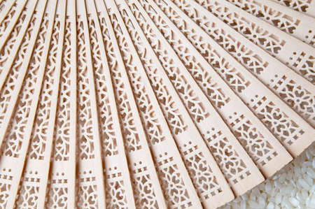 Hand fan on top of white rice backgroundの写真素材