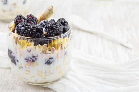 blackberry yogurt parfait in a glass cup on a white tablecloth closeupの写真素材