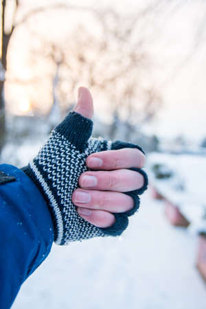 Male hand showing thumbs up in winter gloves outdoorsの写真素材
