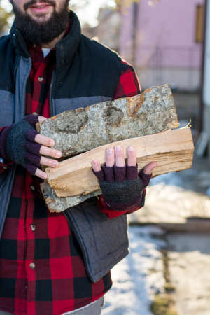 Man carrying firewood in the front yardの写真素材