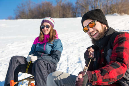 Happy young couple sledding down the hillの写真素材