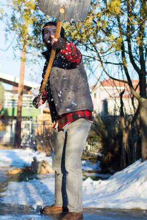 bearded man shoveling snow wearing a shirt and a westの写真素材