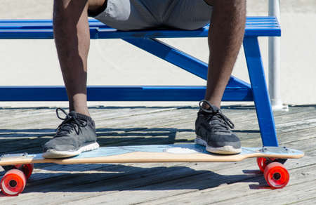 Male feet on skateboard while sitting on a bench