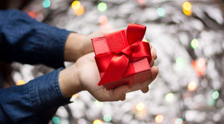 Male holding a red present with colorful backgroundの写真素材