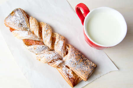 Braided puff pastry with jam and a glass of milkの写真素材