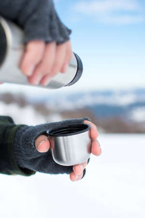 Man using a thermos in on a snowy mountainの写真素材