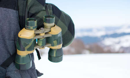 Man with binoculars exploring snowy mountain sceneryの写真素材