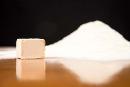 Yeast cube and flour pile on a baking tableの写真素材