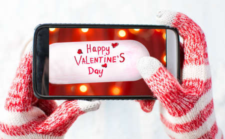 Hands in gloves taking a photo of Valentines day cardの写真素材