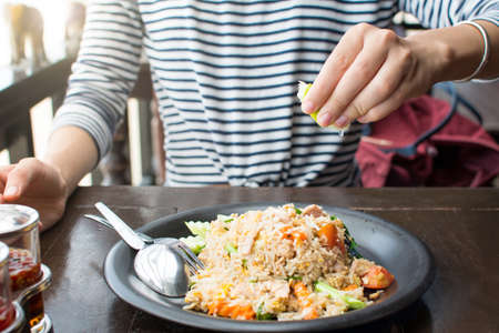 Female hand squeezing lime on fried rice mealの写真素材