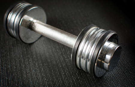 Metal dumbbell on a black yoga matの写真素材