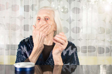 Senior woman applying face cream at homeの写真素材