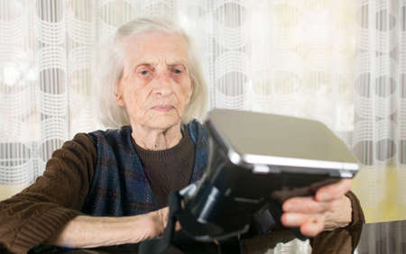 Grandma trying to use VR goggles at homeの写真素材
