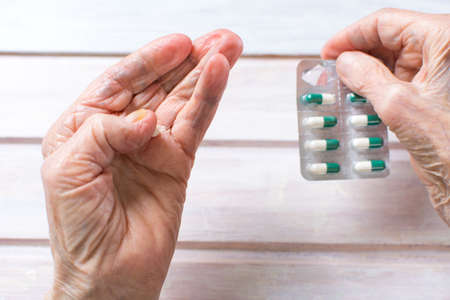 Senior woman hands taking out pill from the packageの写真素材